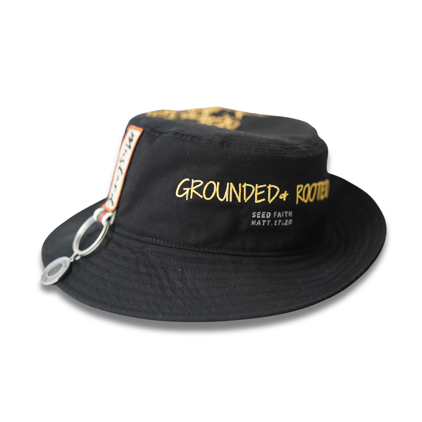 Faith-based black bucket hat featuring gold ‘Grounded & Rooted’ embroidery with Matthew 17:20 scripture, side ‘Mustard’ patch, and chrome Seed Faith keychain.