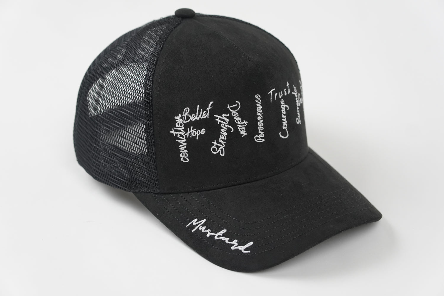 Side view of the Cotton Faith black suede trucker hat featuring embroidered faith-based words like Belief, Strength, and Trust, with mesh paneling and "Mustard" stitched on the brim.